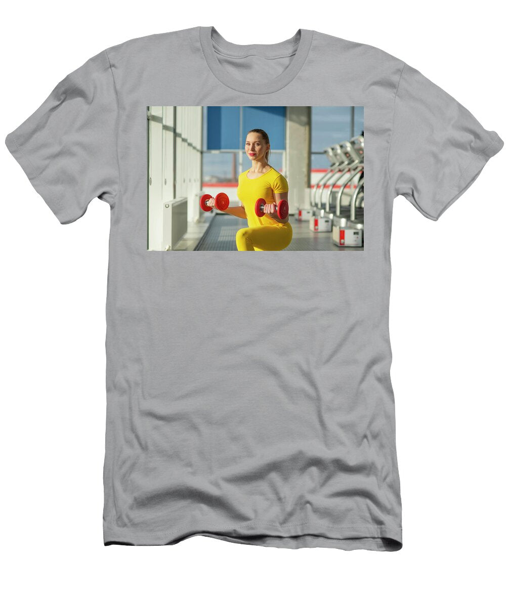 Physically Fit Pretty Woman At the Gym Exercising with Dumbbells to Strengthen Arms and Biceps Maria Kray T-Shirt