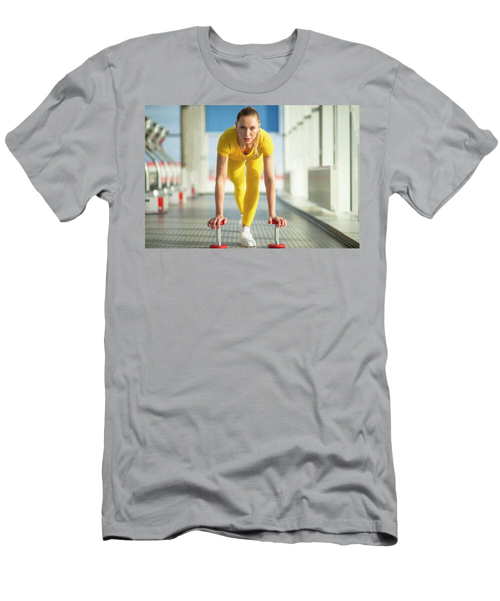 Physically Fit Woman At the Gym with Dumbbells Ready to Strengthen Her Arms and Biceps Maria Kray T-Shirt